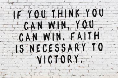 Beyaz tuğla duvara zekice alıntılar yazılı siyah bir yazı.