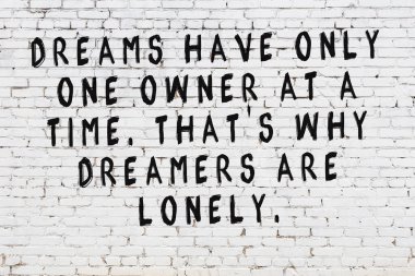 Beyaz tuğla duvar ve bilgece alıntıların yazılı olduğu siyah yazı.