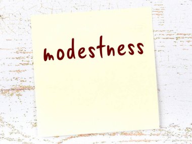 Tevazu hakkında hatırlatma kavramı. Tahta duvarda üzerinde yazı olan sarı yapışkan kağıt.