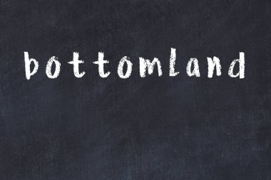 Tebeşir el yazısıyla yazılmış dipsiz araziler siyah masanın üzerinde.