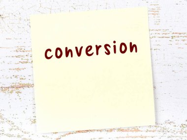 Tahta duvarda el yazısıyla yazılmış sarı yapışkan bir not var.