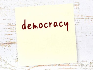Demokrasiyi hatırlatma kavramı. Tahta duvarda üzerinde yazı olan sarı yapışkan kağıt.