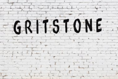 Beyaz tuğla duvara siyah boya ile yazılmış bir taş..