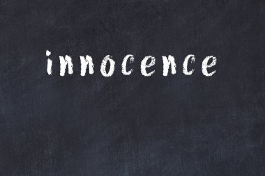 Tebeşir el yazısıyla yazılmış masumiyet siyah masada.