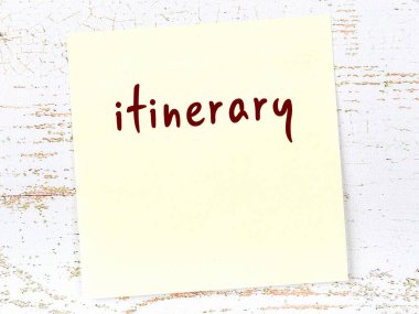 Seyahat programını hatırlatma kavramı. Tahta duvarda üzerinde yazı olan sarı yapışkan kağıt.