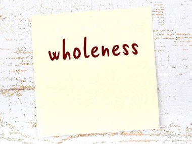 Tahta duvardaki sarı yapışkan notta el yazısıyla yazılmış bütünlük var.