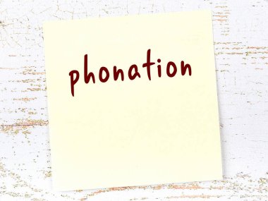 Seslendirmeyi hatırlatma kavramı. Tahta duvarda üzerinde yazı olan sarı yapışkan kağıt.