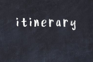 Tebeşir el yazısıyla yazılmış seyahat programı siyah masada.