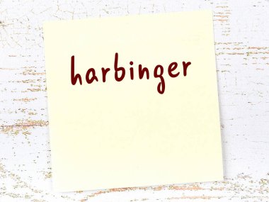 Tahta duvarda el yazısıyla yazılmış sarı yapışkan bir not var.