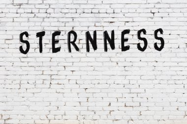 Yazı sertliği beyaz tuğla duvara siyah boya ile yazılmış..