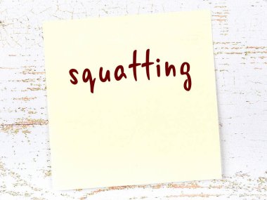 Ahşap duvarda el yazısıyla yazılmış sarı yapışkan bir not var.