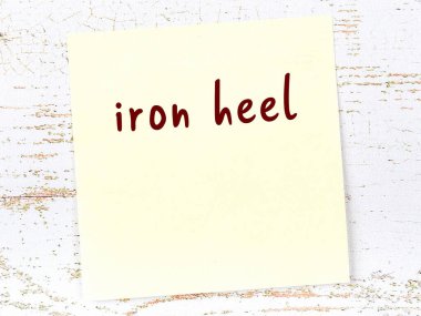 Demir topuğu hatırlatma kavramı. Tahta duvarda üzerinde yazı olan sarı yapışkan kağıt.