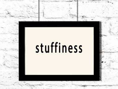 Siyah ahşap çerçeve, beyaz tuğla duvarda yazılar asılı. 