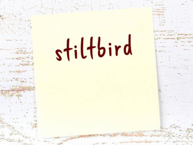 Tahta duvarda el yazısıyla yazılmış sarı yapışkan bir not var.