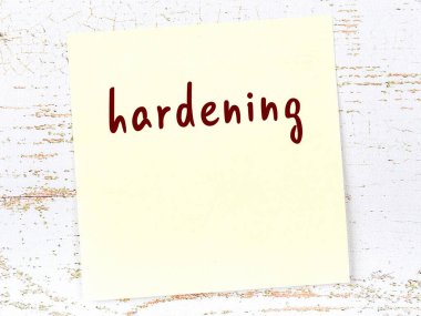 Tahta duvardaki sarı yapışkan notta elle yazılmış yazılar sertleşiyor.