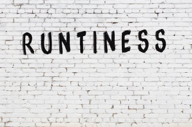 Beyaz tuğlalı duvar. Üzerinde yazı var. Elle yazılmış siyah boya.