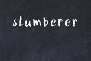 Tebeşir el yazısıyla yazılmış yazı siyah masada uyukluyor.