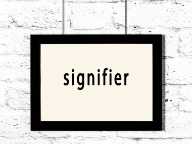 Siyah ahşap çerçeve, beyaz tuğla duvarda yazılar asılı. 