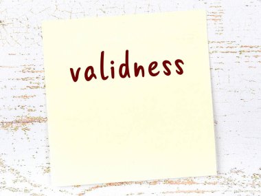 Tahta duvarda elle yazılmış geçerliliği olan sarı yapışkan bir not.