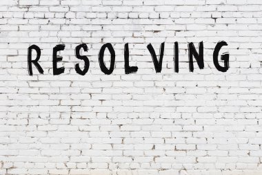 Üzerinde yazı olan beyaz tuğla duvar siyah boyayla el yazısıyla çözülüyor.