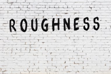 Beyaz tuğlalı duvar, yazı pürüzlü ve siyah boyayla yazılmış.