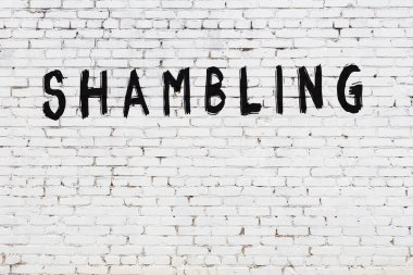 Üzerinde yazı olan beyaz tuğla duvar siyah boyayla el yazısıyla darmadağın olmuş.