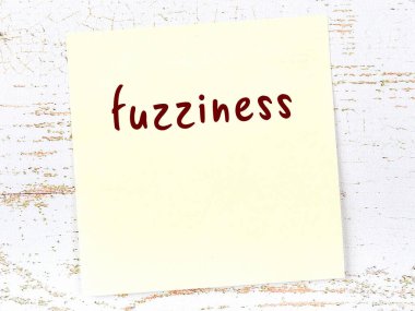 Tahta duvardaki sarı yapışkan notta elle yazılmış bulanıklık var.