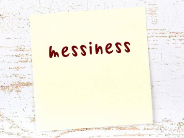 Tahta duvardaki sarı yapışkan notta el yazısı dağınıklığı var.