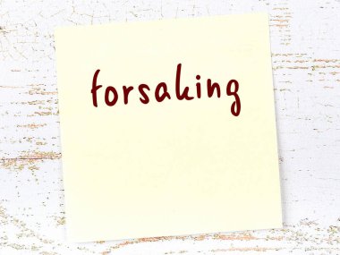 Tahta duvardaki sarı yapışkan notta el yazısıyla yazılmış bir yazı var.