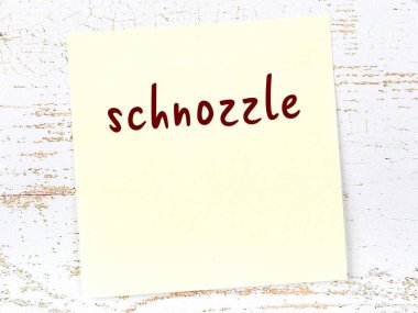 Tahta duvardaki sarı yapışkan notta el yazısıyla yazılmış burun deliği var.