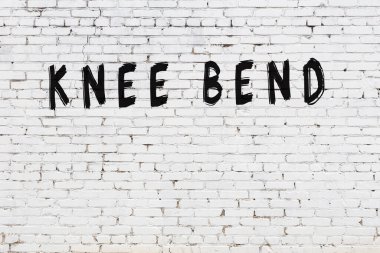 Üzerinde yazı olan beyaz tuğla duvar. Diz çöküp siyah boyayla yazılmış.