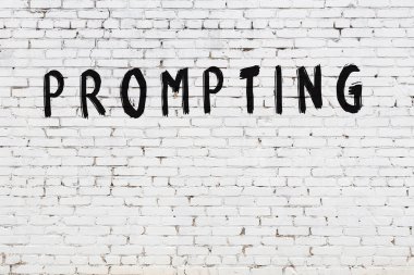 Üzerinde yazı olan beyaz tuğla duvar siyah boyayla el yazısını tetikliyor.