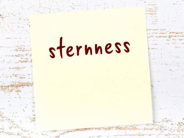 Tahta duvardaki sarı yapışkan notta el yazısı sertliği var.