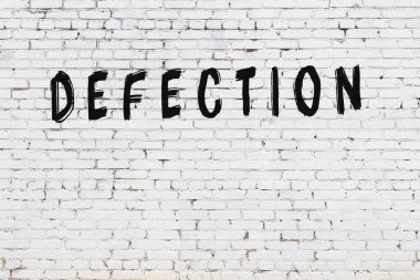 Beyaz tuğladan duvar, el yazısıyla siyah boya ile iltica etmiş.