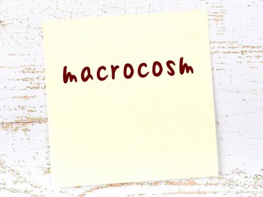 Makro evreni hatırlatma kavramı. Tahta duvarda üzerinde yazı olan sarı yapışkan kağıt.