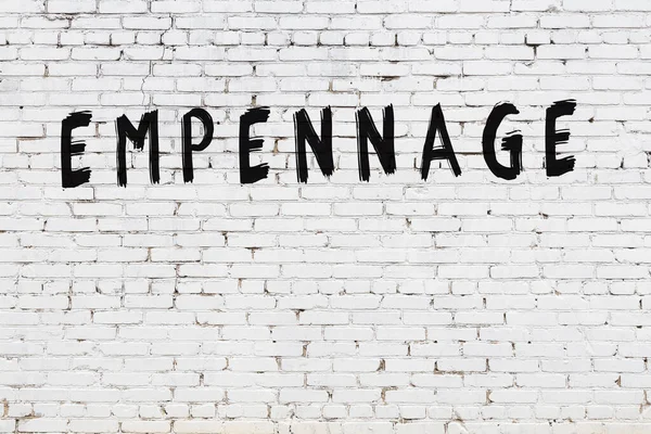 Yazı, beyaz tuğla duvara siyah boya ile yazılmış..