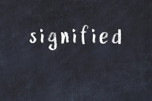 Tebeşir el yazısıyla yazılmış yazı siyah masaya işlenmiş.