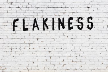 Beyaz tuğlalı duvar. Üzerinde yazı var. El yazısı siyah boya.