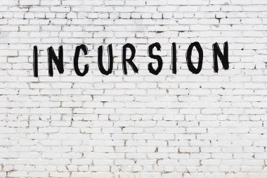 Yazıt baskını beyaz tuğla duvara siyah boya ile yazılmış..