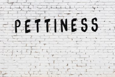 Beyaz tuğlalı duvar. Üzerinde yazı var. El yazısı siyah boya.