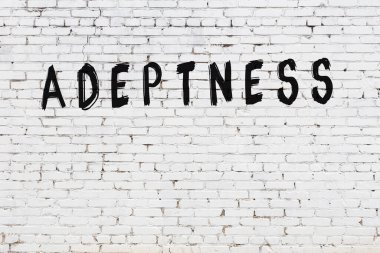 Beyaz tuğlalı duvar. Üzerinde yazı var. Elle yazılmış siyah boya.