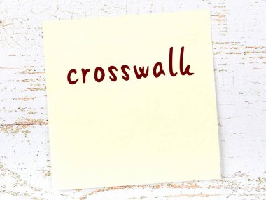 Tahta duvardaki sarı yapışkan notta el yazısıyla yazılmış yaya geçidi var.