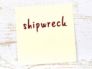 Tahta duvardaki sarı yapışkan notta el yazısıyla yazılmış gemi enkazı var.