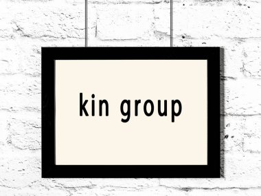 Beyaz tuğla duvara asılı siyah ahşap çerçeve ve yazı grubu. 