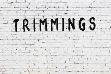 Beyaz tuğlalı duvar, siyah boyalı el yazısıyla süslenmiş.