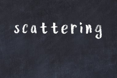 Tebeşir el yazısıyla yazılmış yazı siyah masaya saçılmış.