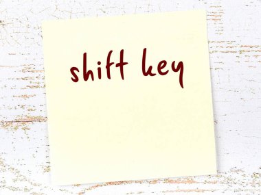 Vardiya anahtarını hatırlatma kavramı. Tahta duvarda üzerinde yazı olan sarı yapışkan kağıt.