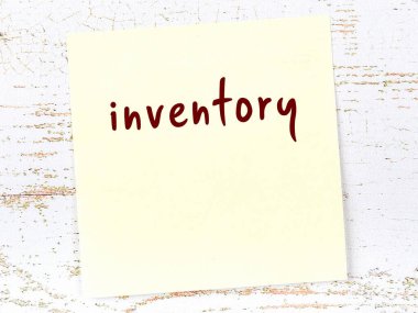Tahta duvarda el yazısıyla yazılmış envanterle birlikte sarı yapışkan bir not var.
