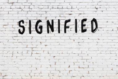 Yazı, beyaz tuğla duvara siyah boya ile yazılmış..