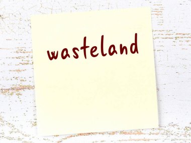 Tahta duvardaki sarı yapışkan notta el yazısıyla yazılmış çorak arazi var.